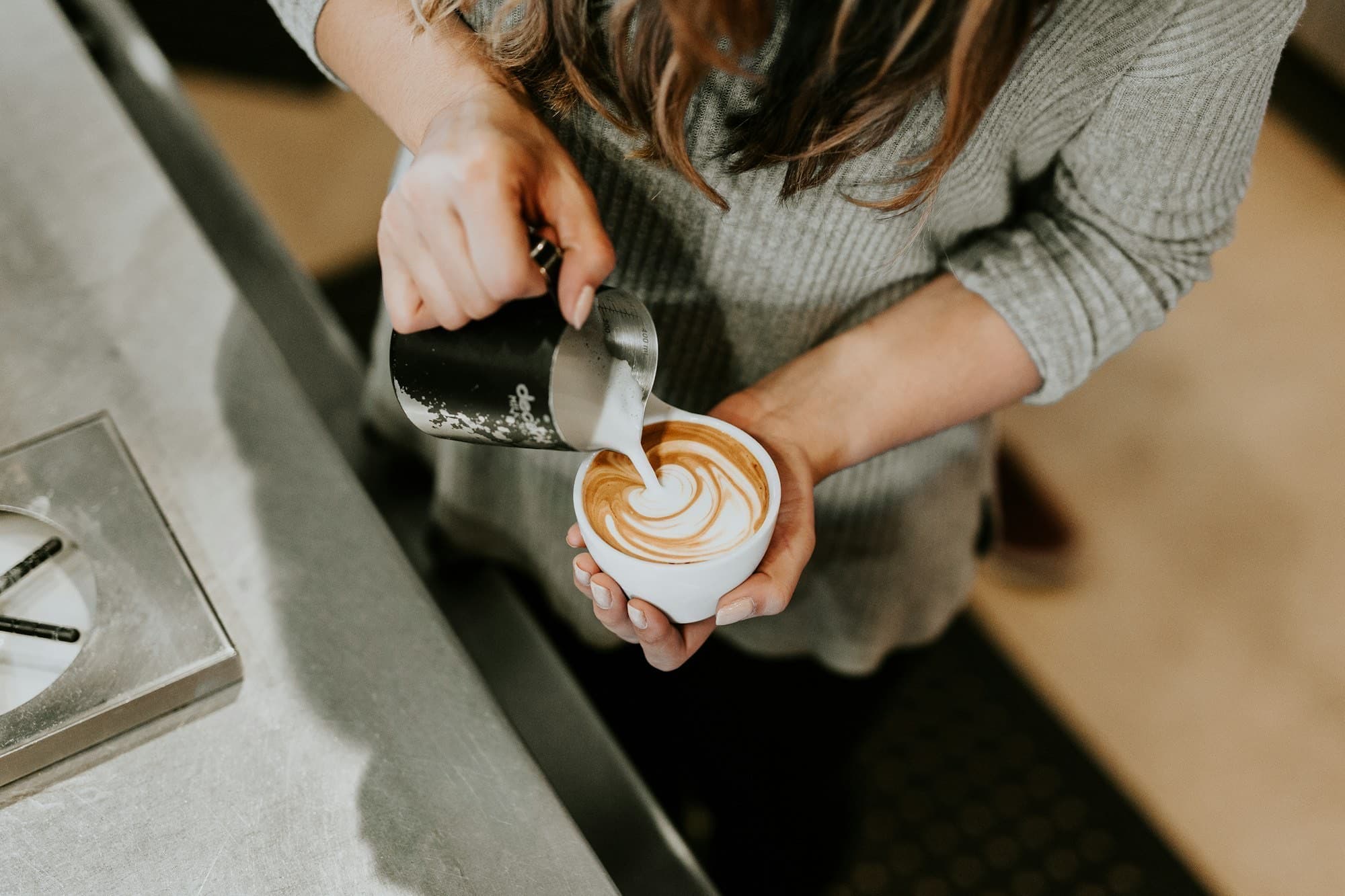 A barista pouring coffee at the café counter